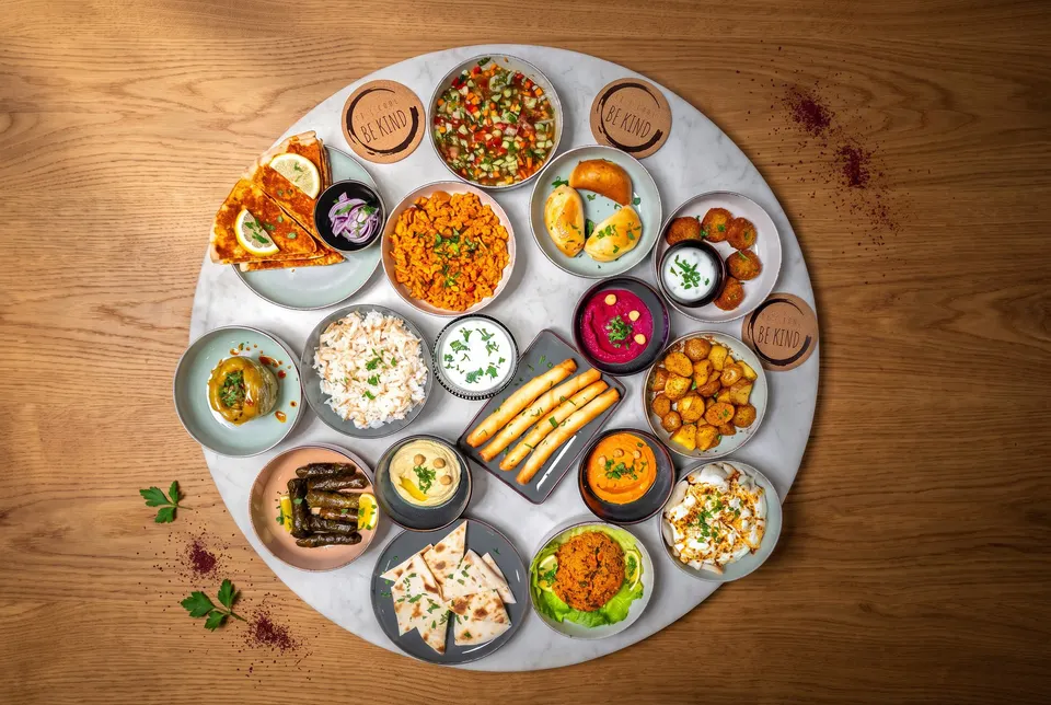 Round mezze platter with many small bowls: hummus, beetroot hummus, muhammara, yoghurt, salads, falafel, cheese cigars, sarma and flatbread (illustrative image)
