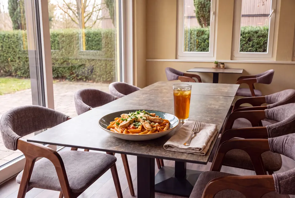 Teller Penne an Tomatenrahmsauce mit Pouletgeschnetzeltem und Parmesan am Fenster des Lokals (Symbolbild)